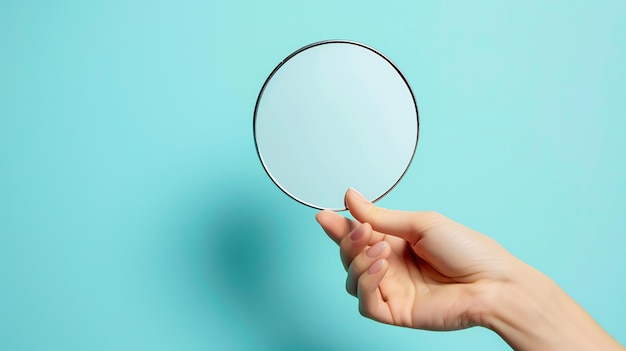 Een hand die een ronde spiegel vasthoudt de spiegel reflecteert de hand de achtergrond is een lichtblauwe kleur