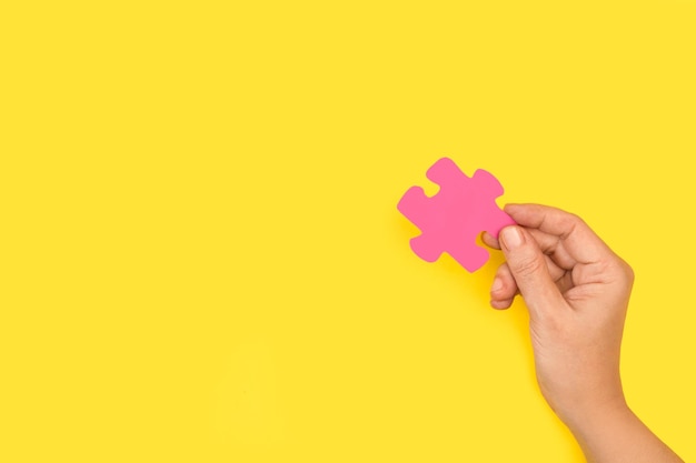 Een hand die een roze puzzelstukje vasthoudt