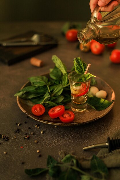 Een hand giet olijfolie in een serveerglas met Italiaanse Caprese-salade erin. Gezonde salade