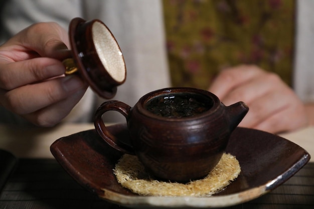 Een hand houdt een kopje thee vast en giet de koffie erin.