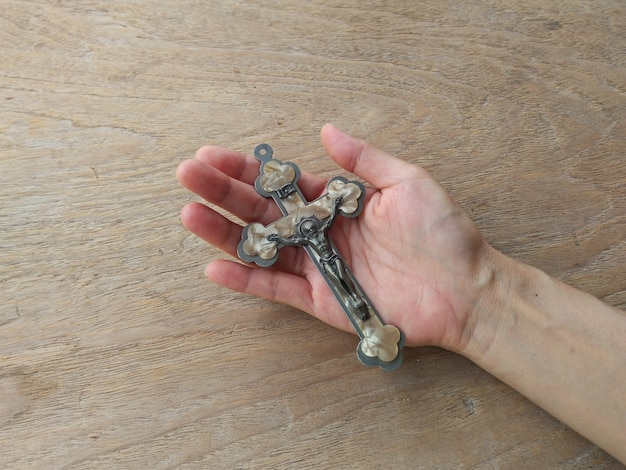 Een hand houdt het kruis met kruisiging van Jezus Christus