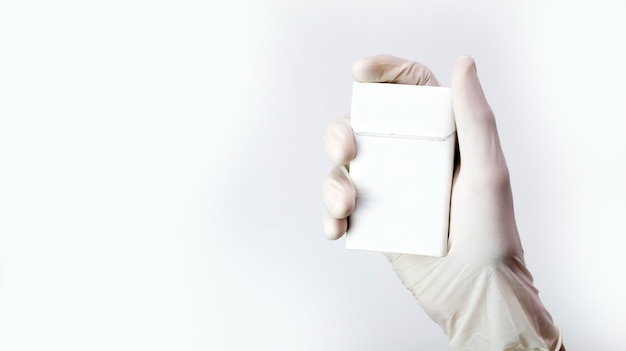 Een hand in een medische handschoen houdt een wit pakje sigaretten vast, een antirookconcept