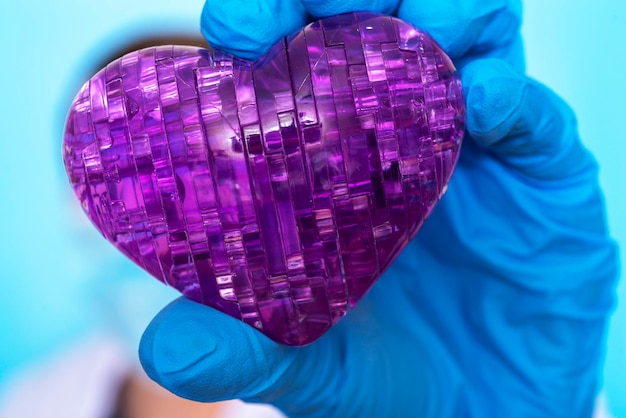 Foto een hand in een medische handschoen houdt het hart vast het concept van geneeskunde en revalidatie