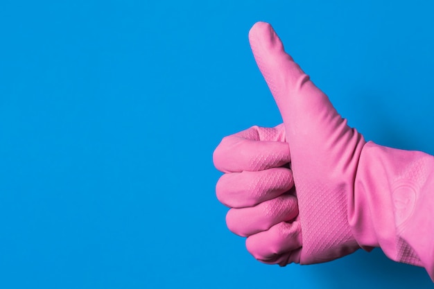 Een hand in een roze rubberen handschoen met de duim omhoog