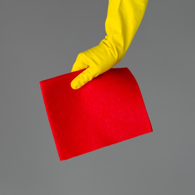 Een hand in een rubberen handschoen houdt een heldere microfiber stofdoekreiniging.