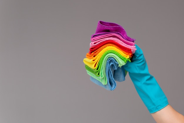 Een hand in een rubberen handschoen houdt een set gekleurde microvezeldoeken vast