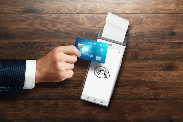 Een hand met een creditcard voert een betaling uit op een elektronische terminal. Betaling per kaart, contactloos betalingssysteem, aankopen, elektronisch geld.
