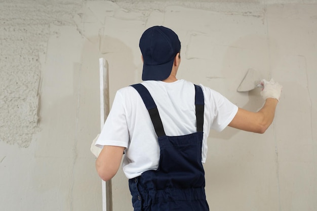 Een hand met een spatel Werknemers brengen stopverf aan op de muur met een spatel Lijnt de muur uit