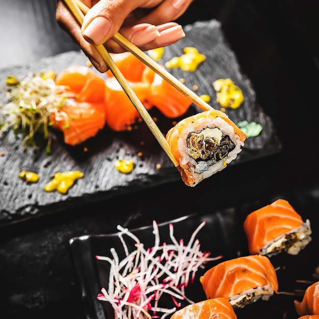 Foto een hand met een sushirol met stokjes