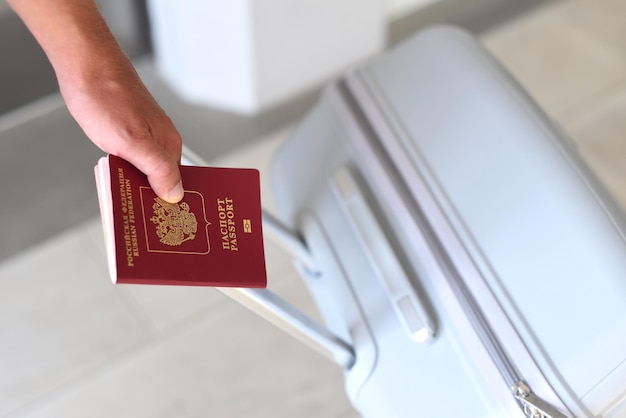 Een hand met Russisch paspoort en koffer