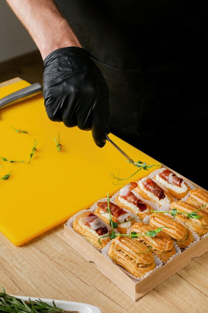 Een hand van een chef-kok die een dienblad met gourmet gebak met groene kruiden versiert om de bereiding van voedsel te illustreren