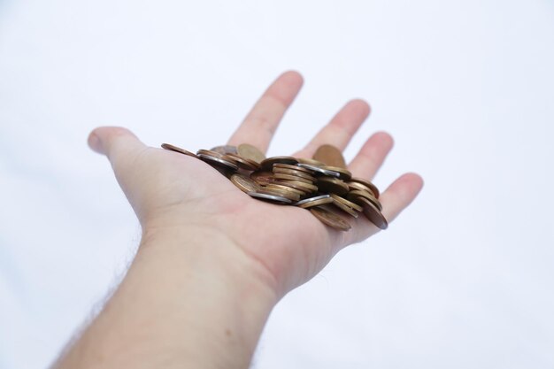 Foto een hand van een persoon met vallende munten en een witte achtergrond