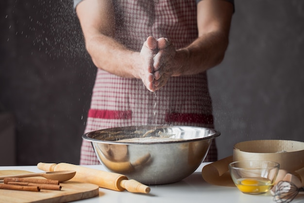 Een handvol bloem met ei op een rustieke keuken. Kneed het deeg tegen de muur van mannenhanden