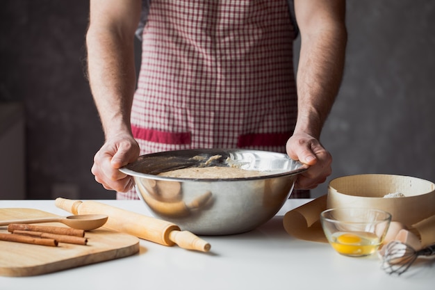 Een handvol bloem met ei op een rustieke keuken. Kneed het deeg tegen de tafel van mannenhanden