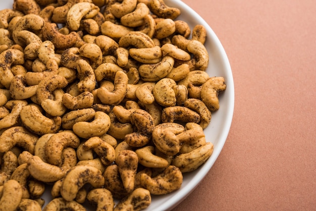 Een handvol geroosterde gekruide cashewnoten of masala kaju geserveerd in een kom, selectieve focus