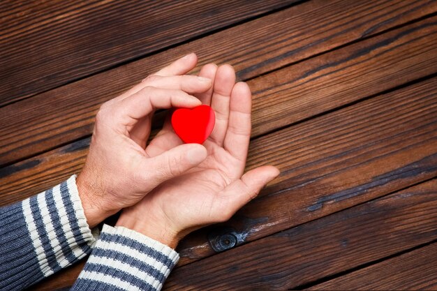 Een hart in handen op valentijnsdag op een houten vakantie als achtergrond