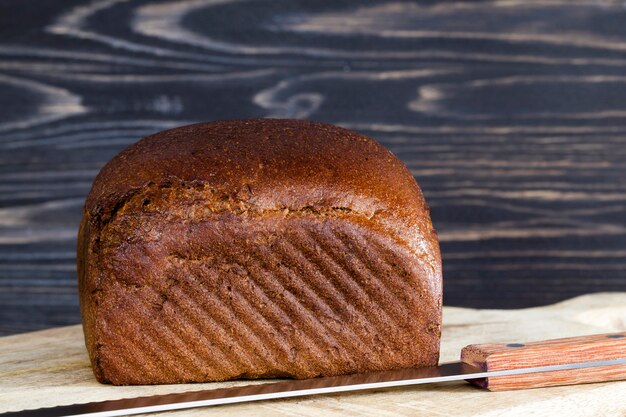 Een heel brood van zwart brood op een snijplank