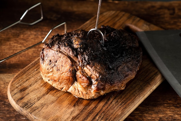 Een heel gebakken stuk vlees Een stuk varkensvlees in kruiden gekookt in de oven op een houten plank