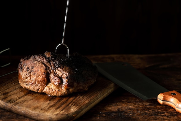 Een heel gebakken stuk vlees Een stuk varkensvlees in kruiden gekookt in de oven op een houten plank