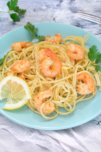 Een heerlijk recept voor spaghetti met garnalen, versierd met citroen en peterselie.