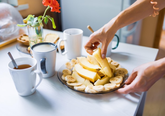 Een heerlijk voedzaam ontbijt met thee en koffie, in stukjes gesneden meloen en banaan, verse toast met boter en noten staan 's ochtends op tafel te wachten op gezelschap of familie in gezellige huiskeuken