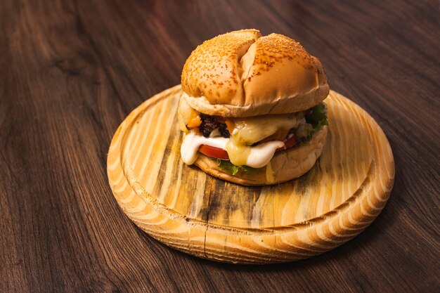 Een heerlijke hamburger met verschillende soorten kaas op een houten bord.