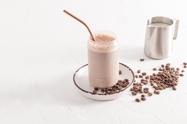 Een heerlijke koffie cappuccino latte met schuim in een modern glas in de vorm van een bierblik staat op een bord tussen koffiebonen witte achtergrond