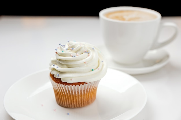 Een heerlijke vanille cupcake met slagroom en een kopje cappuccino koffie