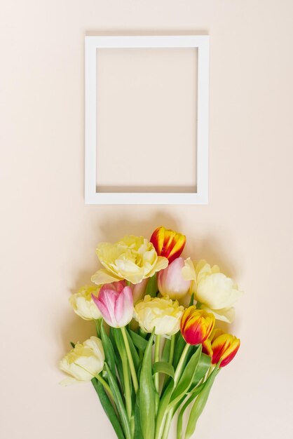 Een helder lenteboeket tulpen en een tekstkader op een beige achtergrond met kopieerruimte Platliggende wenskaart