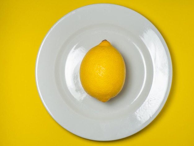 Een hele citroen op een bord op een gele achtergrond Citrus op tafel Lichte achtergrond Gezonde verrijkte voeding voor een dieet