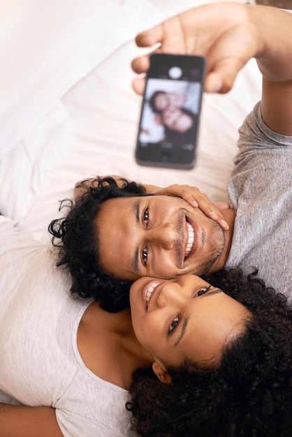 Een herinnering vastleggen Een schattig stel maakt een selfie op het bed