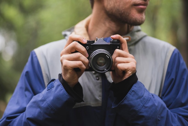 Een hipster die een foto maakt met een oude vintage camera buitenshuis