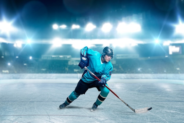 Foto een hockeyspeler schaatsen met stok op ijs arena, schijnwerpers op achtergrond. mannelijke persoon in helm, handschoenen en uniform speelspel