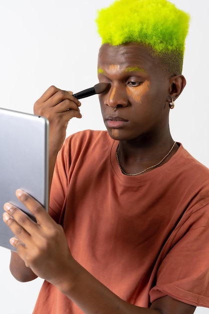 Een homoseksuele zwarte man die make-up opdoet LGTBI-concept corrigeert onvolkomenheden met een spiegel
