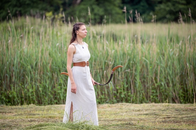 Een Hongaarse vrouw in een linnen jurk met een strik staat op het veld