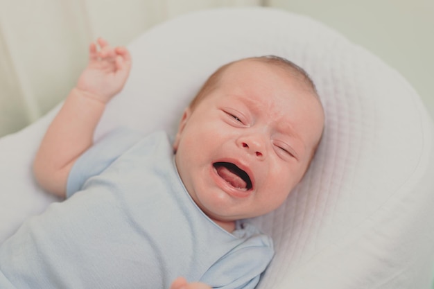 Een hongerige baby huilt in de wieg Baby huilt Kinderemoties Pijn tijdens tandjes krijgen Een hongerig kind Kinderkoliek in de maag