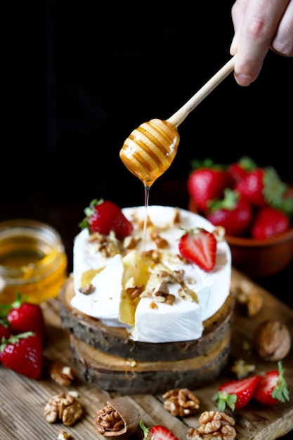 Een honingstok giet honing over een camembert