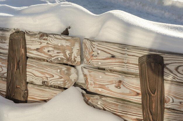 Een houten bank met sneeuw erop en een bord met de tekst "winter".