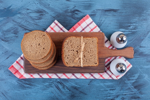Een houten bord van bruin brood en kruiden op een tafellaken.
