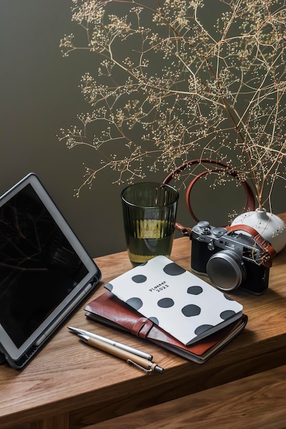 Een houten bureau thuis met een tablet notebooks een camera en een glas water Kantoor aan huis