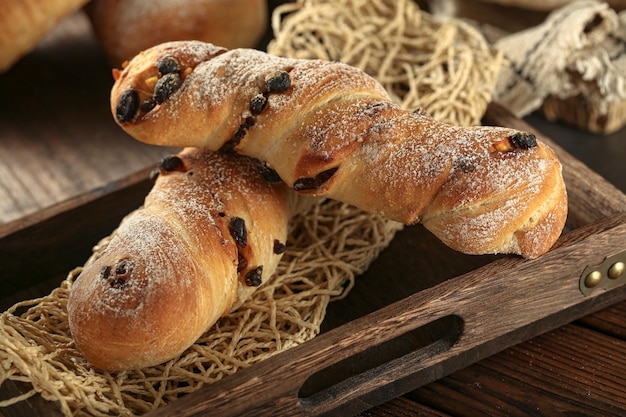 Een houten dienblad met broden en een houten dienblad met daarop een bagel met zwarte rozijnen