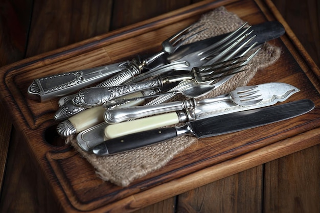 Een houten dienblad met vorken en messen erop