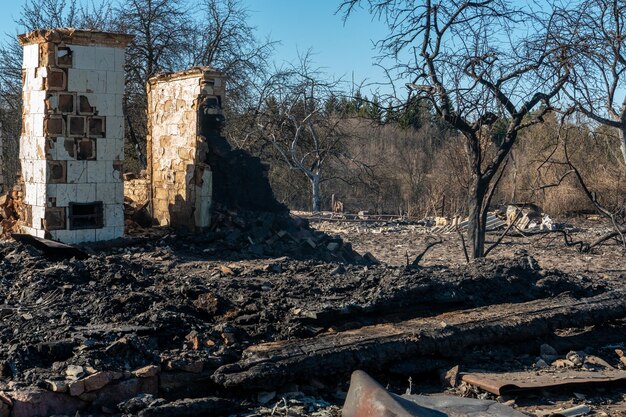 Een houten huis in het dorp is afgebrand vanwege een bosbrand Verkoolde planken en verschillende dingen liggen op de grond bedekt met as en rook