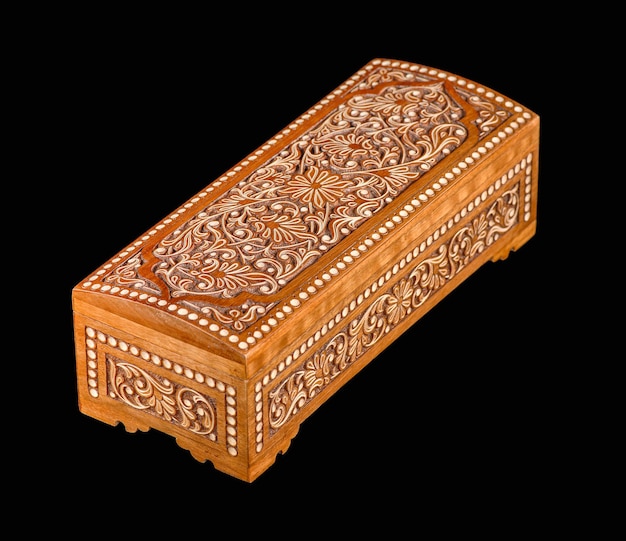 Een houten kist met traditioneel artistiek snijwerk geïsoleerd op een zwarte achtergrond
