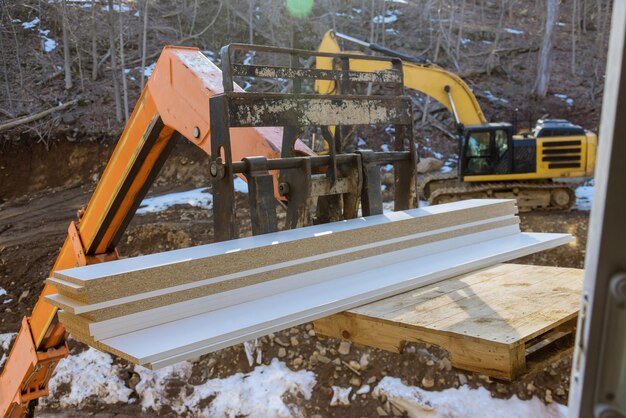 Een houten plank die wordt opgeheven door een boomtruck heftruck in de bouwmaterialen met constructie