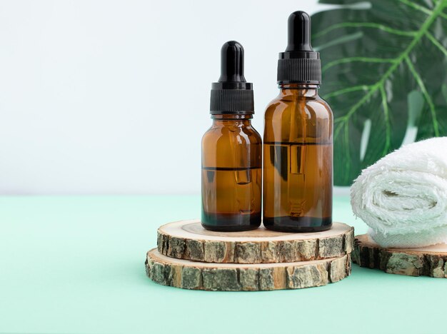 Een houten podium een wit servet twee flessen met een pipet gevuld met olie of essence Lichaamsverzorging concept natuurlijke spa cosmetica