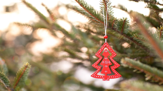 een houten rode kerstboom hangt aan de takken van een dennenboom