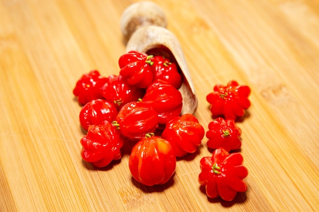 Een houten schaal met rode en gele paprika's staat op een houten ondergrond.