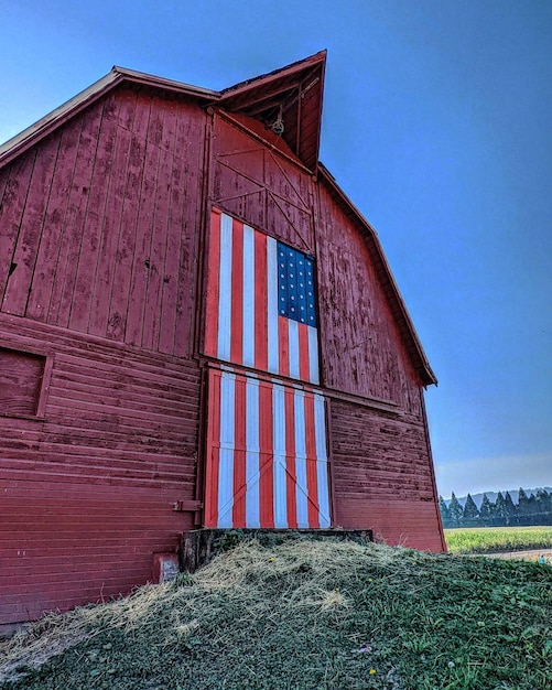 Een houten schuur met een deur met het ontwerp van de Amerikaanse vlag, met gras ervoor op een zonnige dag