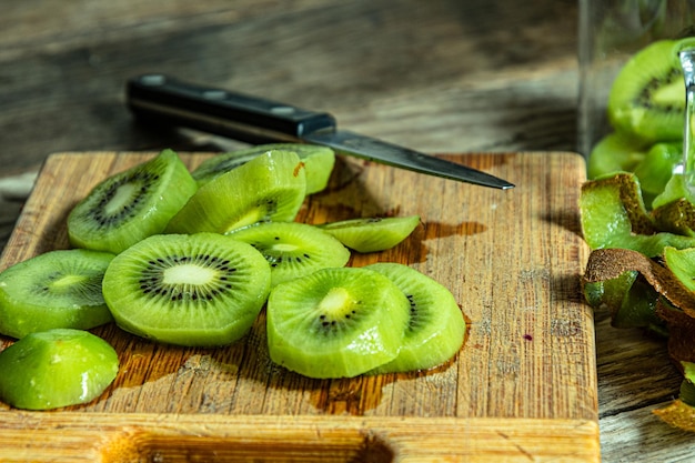 Een houten snijplank met gesneden kiwi's en een mes.